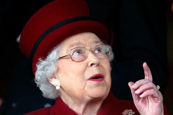 Mulher com chapéu vermelho apontando o dedo para cima