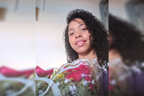 Foto colorida de mulher com cabelo com cachos segurando flores
