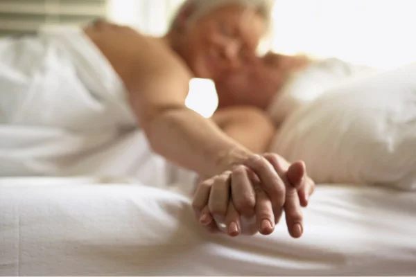 Foto colorida de um casal na cama - Metrópoles
