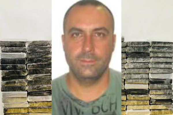 Retrato de homem branco, com barba por fazer, cabelo raspado com entrada, atrás do qual há tijolos embrulhados com saco plástico preto, empilhados em frente a parede branca - Metrópoles