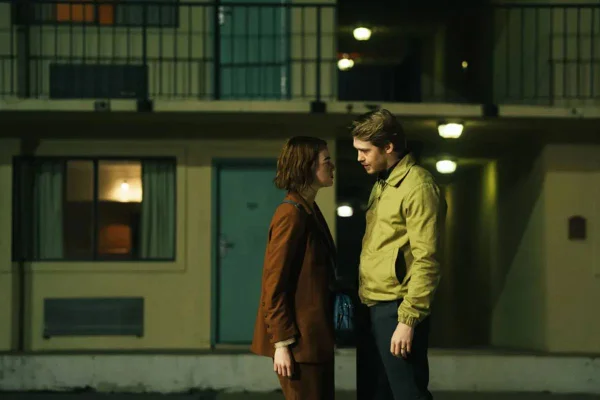 Uma mulher de casaco vermelho beija um homem de casaco amarelo. Cena do filme Tipos de Gentileza, de Yorgos Lanthimos
