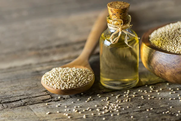 Foto colorida de colher com sementes de quinoa ao lado pode com óleo - Metrópoles