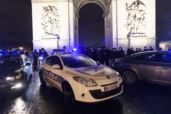 imagem colorida de uma viatura da polícia da frança em frente ao arco do triunfo, em paris