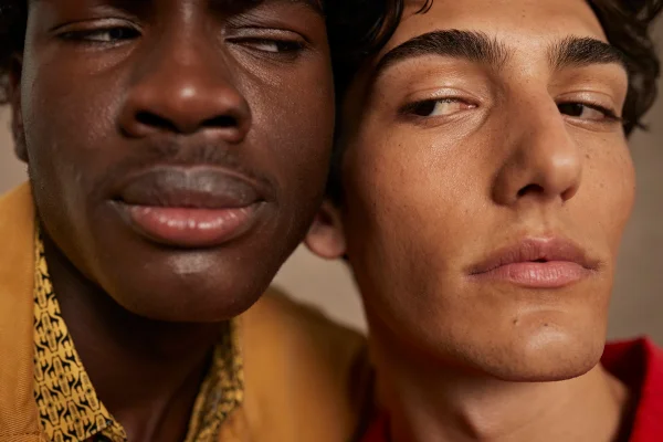 dois homens, um branco e um negro com o rosto perto da imagem
