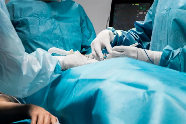 Foto colorida de sala de cirurgia com pessoas vestidas de azul - Metrópoles.