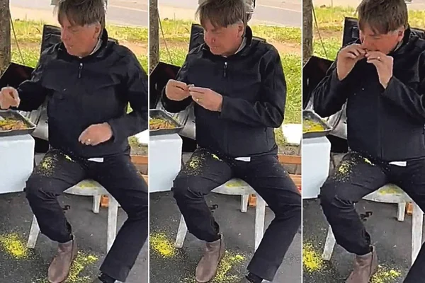 Bolsonaro aparece em vídeo comendo churrasco com farofa em comércio local de Brasília. Ele usa jaqueta preta, sentado na frente de uma mesa, e sua perna e o chão estão sujos de farofa.