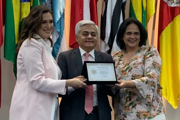 Fotografia colorida de homem segurando diploma com mulheres ao lado