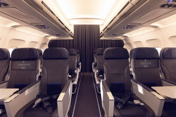 Imagem colorida mostra interior de avião da Latam. Aparecem assentos com a inscrição Premium Economy em poltronas separadas por um corredor - Metrópoles