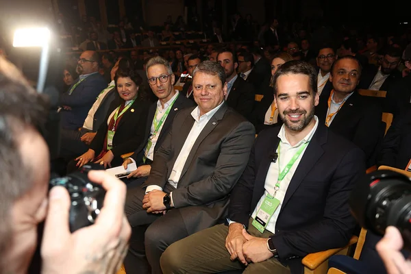 Fotografia colorida mostra Romeu Zema, Tarcísio de Freitas e Eduardo Leite sentados em uma fileira de cadeiras e olhando para o lado - Metrópoles