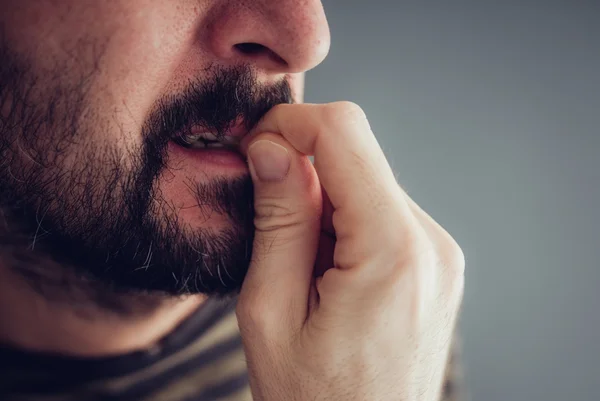 Imagem mostra homem de barba roendo as unhas - Metrópoles