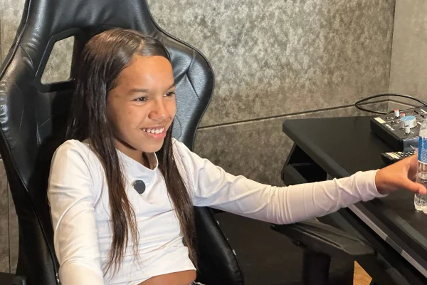 imagem colorida mostra menina de 13 anos sorrindo. ela é negra, tem o cabelo liso e usa uma blusa branca de manga longa