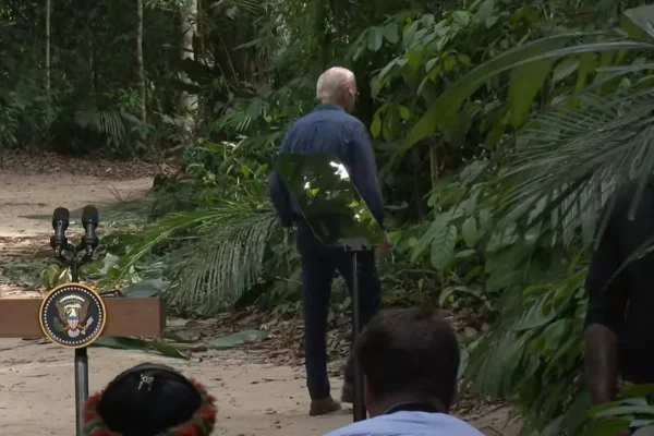 Imagem colorida do presidente Joe Biden entrando na mata