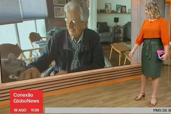 Foto colorida de Fernando Gabeira levando uma mordida de sua gata Renata - Metrópoles