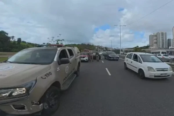 Foto colorida de viatura da Policia Militar durante confronto contra suspeitos em avenida de Salvador
