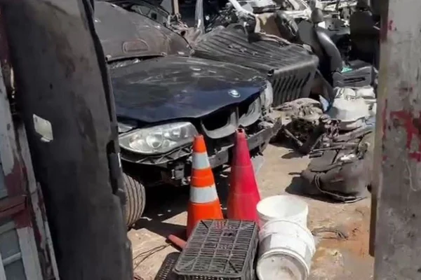 Imagem colorida de uma BMW preta furtada sendo desmanchada - Metrópoles