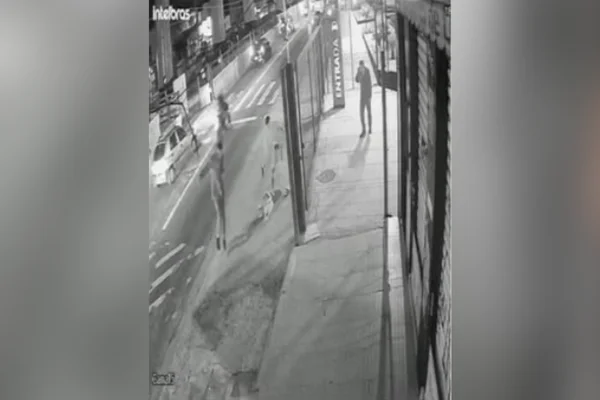 Imagem em preto e branco com homem atirando em cachorro. Metrópoles