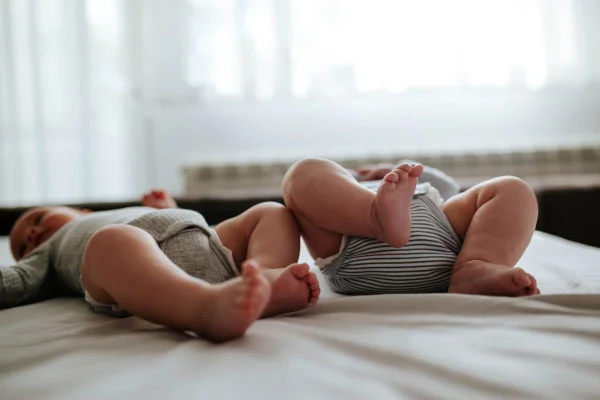foto colorida dos pezinhos de dois bebes gêmeos na cama