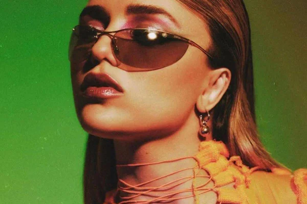 Modelo usa óculos escuro e top amarelo