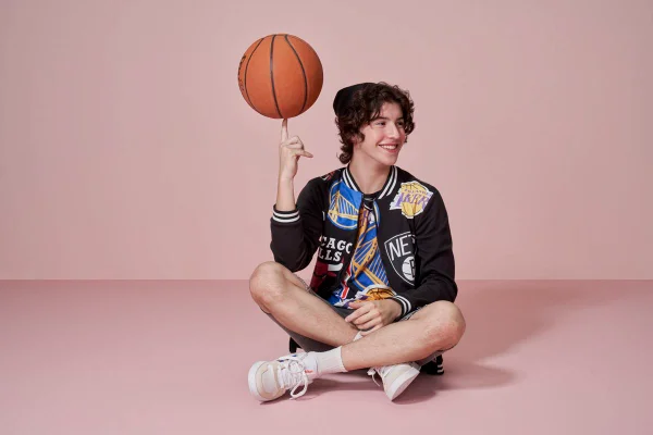 imagem com cor de um menino sentado girando uma bola de basquete