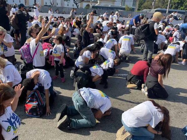 Fiéis se ajoelham no asfalto durante Marcha para Jesus de SP