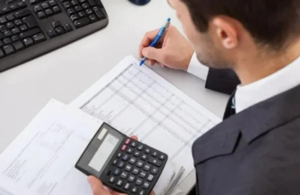 Imagem colorida de um homem calculando impostos - Metrópoles