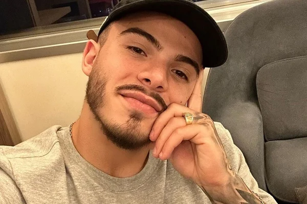 Thomaz Costa posa, pensativo, com uma camisa cinza e boné preto - Metrópoles