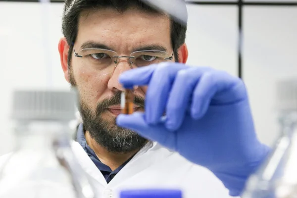 Imagem mostra o pesquisador Mario Murakami no laboratório, de luvas azuis, olhando uma cápsula - Metrópoles