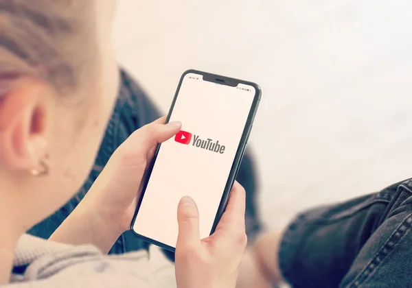 mulher segura celular e na tela aparece a logo do YouTube