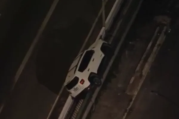 Imagem colorida de carro branco pendurado em mureta de rodovia na zona oeste de SP - Metrópoles