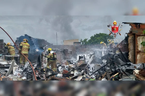 Imagem colorida de bombeiros tentando apagar incêndio em uma casa - metrópoles
