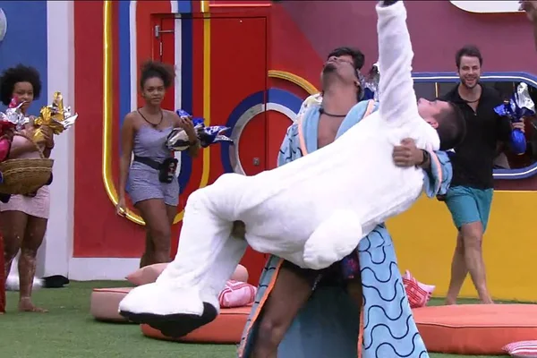 Arthur Aguiar no colo de PA, participantes do BBB22, após o primeiro voltar do paredão falso enquanto outros brothers assistem a comemoração - Metrópoles