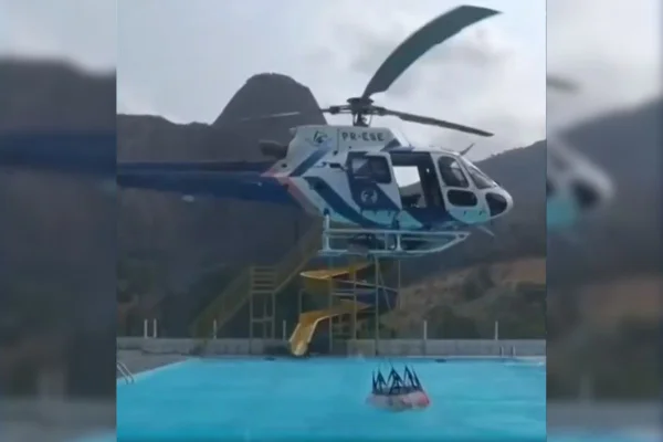 Foto colorida de helicópetro reabastecendo helibalde em piscina - Metrópoles