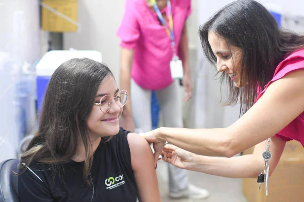 Imagem mostra adolescente recebendo vacina no braço - Metrópoles