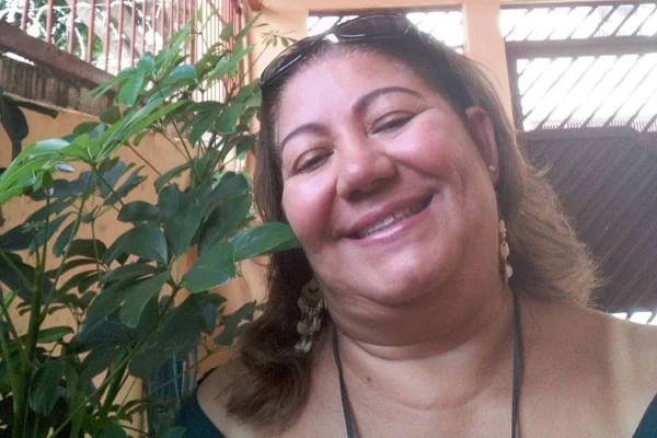 Imagem colorida mostra mulher branca com cabelos castanhos soltos. Ela tem um óculos de sol na cabeça e sorri olhando para a câmera - Metrópoles