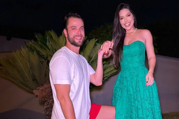 foto colorida de homem ajoelhado sorrindo e segurando mão de mulher, que está em pé - metrópoles
