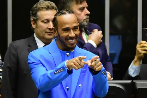 O piloto britânico Lewis Hamilton na Câmara dos Deputados para receber título de cidadão honorário do Brasil. Na foto, ele sorri e aponta para frente no plenário da casa legislativa - Metrópoles