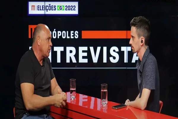 Deputado distrital eleito Wellington Luiz e o repórter Matheus Garzon. Sentados em uma bancada, o deputado usa blusa preta e o repórter, blusa azul