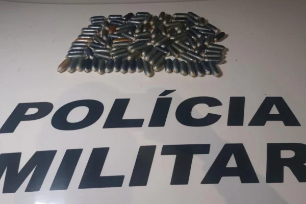 Imagem colorida de cápsulas de cocaína agrupadas no capô de um carro da PM - Metrópoles