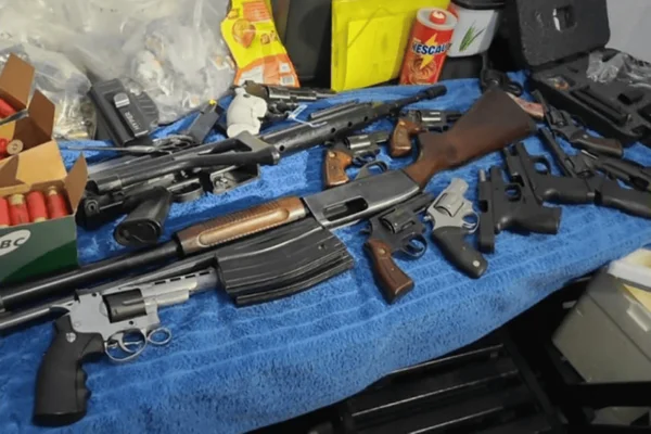 Imagem colorida de armas e drogas agrupadas em cima de uma mesa da polícia - Metrópoles