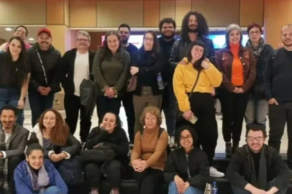 imagem colorida mostra grupo de pessoas em frente à cinema de sp