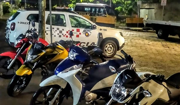 Imagem colorida de viatura da PMSP e motos apreendidas