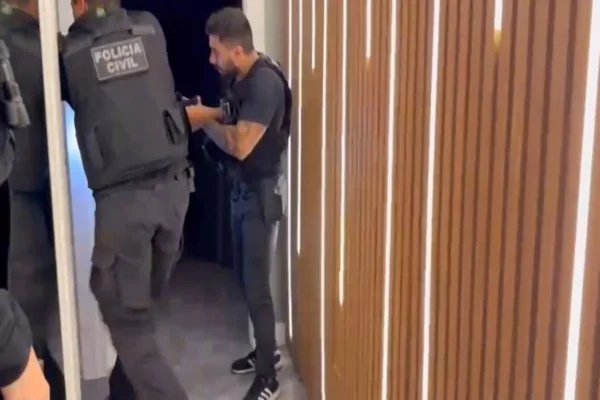 Imagem colorida de policiais civis entrando em uma casa - Metrópoles