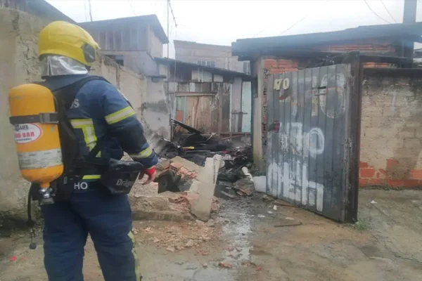 Imagem colorida de um agente do Corpo de Bombeiros em frente à casa que teve incêndio - Metrópoles