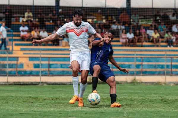 foto colorida de dois jogadores de futebol disputando bola em campo - metrópoles