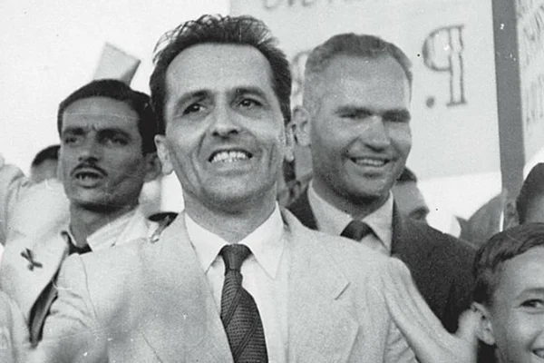 Foto preto e branca de Luiz Carlos Prestes no meio de dois homens de terno - Metrópoles