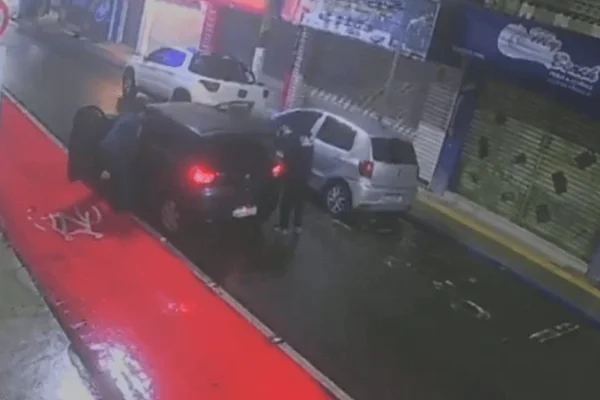 Imagem colorida de criminosos abordando um motorista e um passageiro durante um assalto - Metrópoles