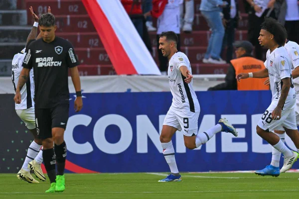 Imagem colorida de jogadores da LDU comemorando ao fundo e jogador do botafogo cabisbaixo - Metrópoles