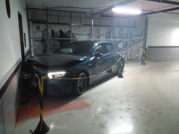 Carro preto batido em garagem do prédio