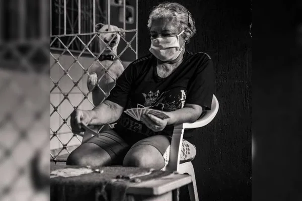 Mulher com máscara joga baralho