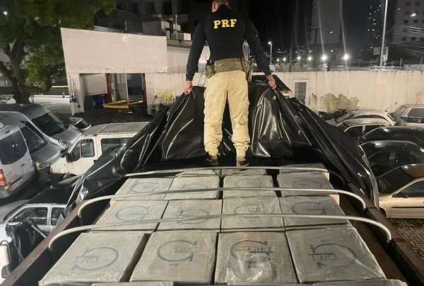 Imagem colorida de agente da PRF em cima de carga apreendida - Metrópoles